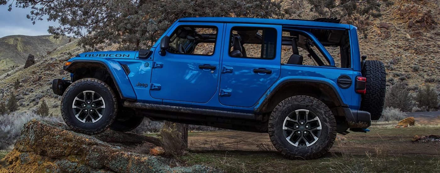 Side of a blue 2026 Jeep Wrangler parked off-road.