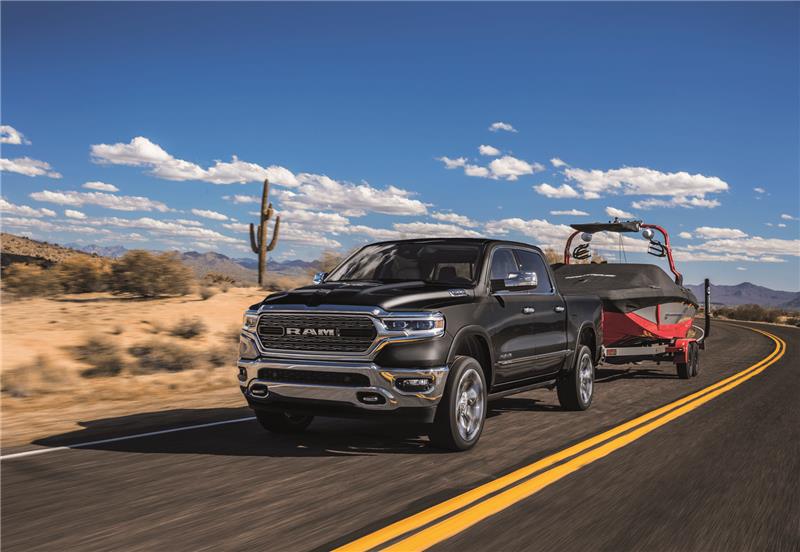 Ram truck hauling boat driving along desert road