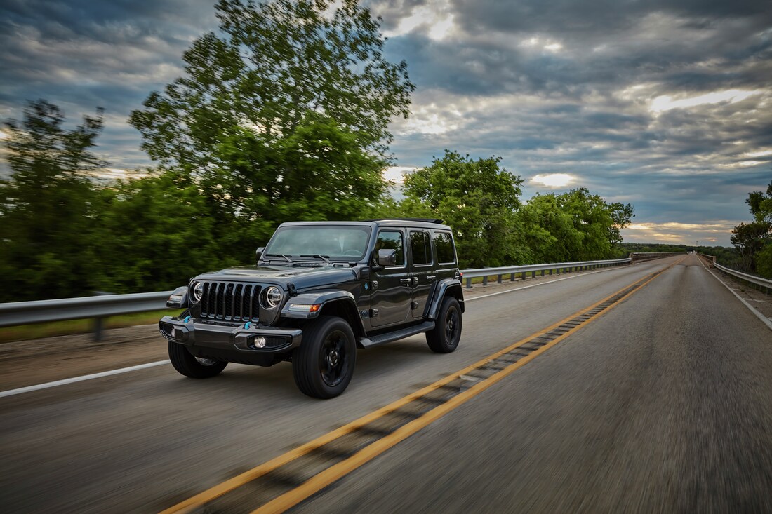Jeep Wrangler 4xe driving on scenic road with motion blur