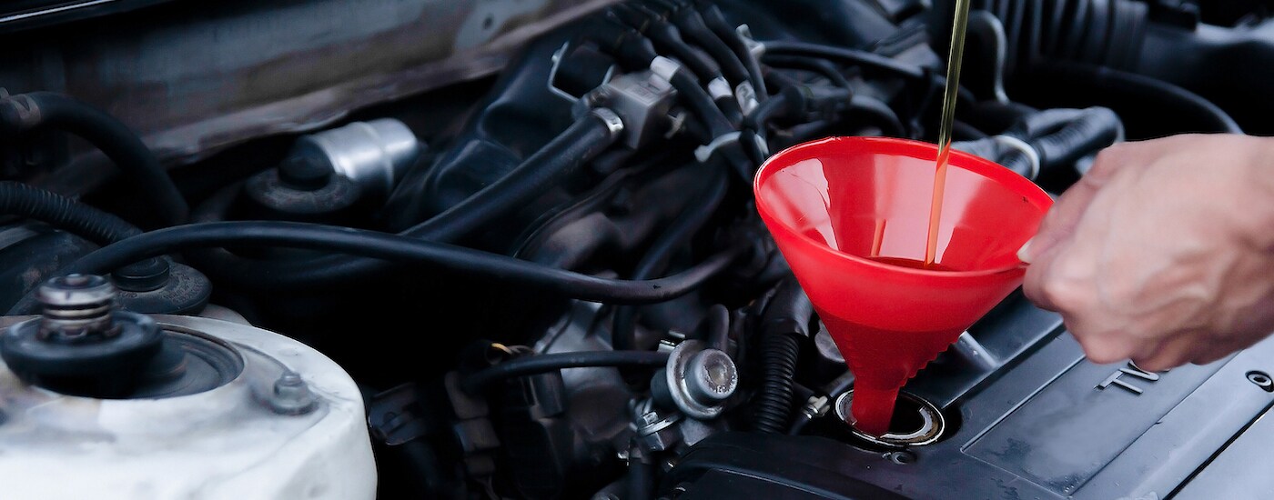 Mechanic pouring oil into a funnel.