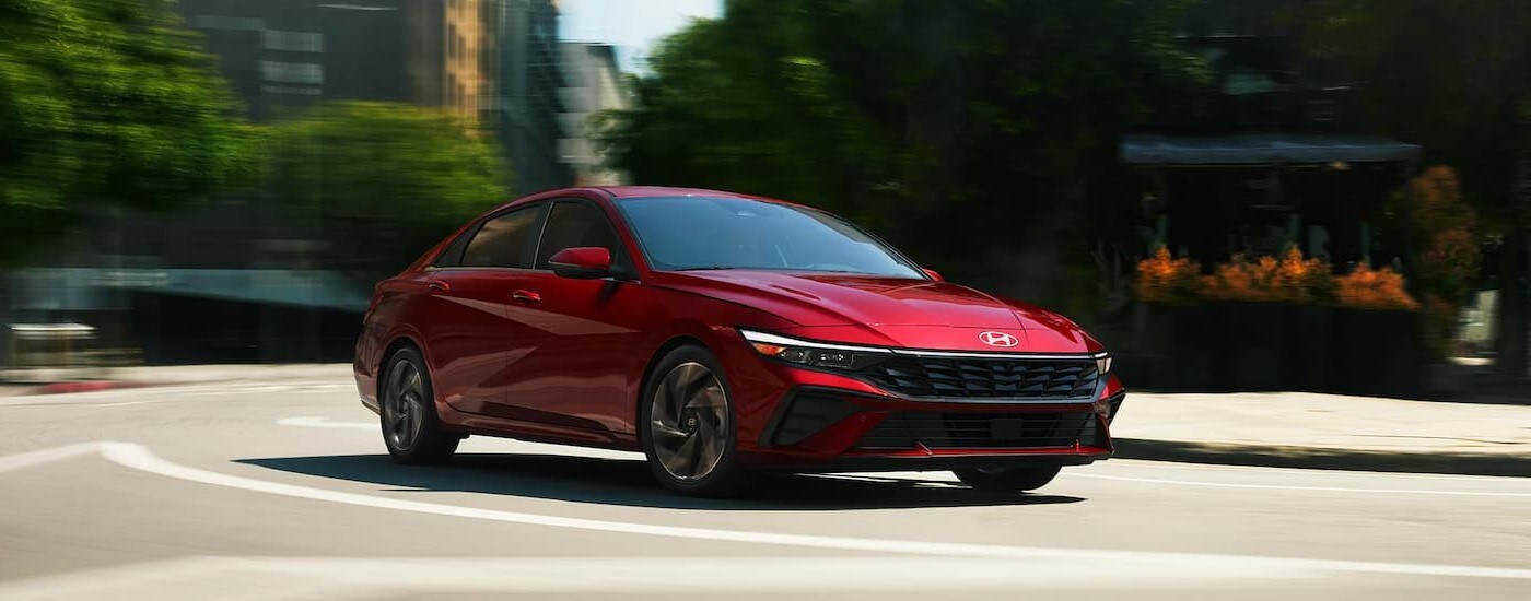 Red 2026 Hyundai Elantra driving around a bend.