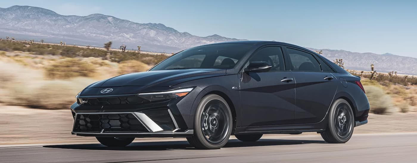 Black 2026 Hyundai Elantra driving down a road.