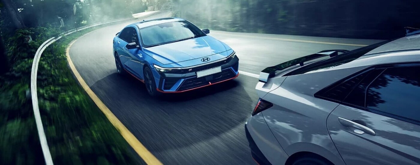 Blue 2026 Hyundai Elantra N driving down a road.