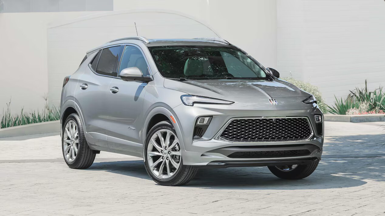 Front and side views of a 2025 Buick Encore GX Avenir in silver, showcased in a modern driveway.