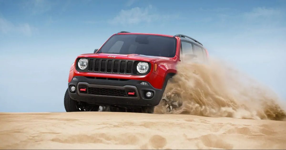 Red 2021 Jeep Renegade Driving In Sand With A Blue Sky.jpg
