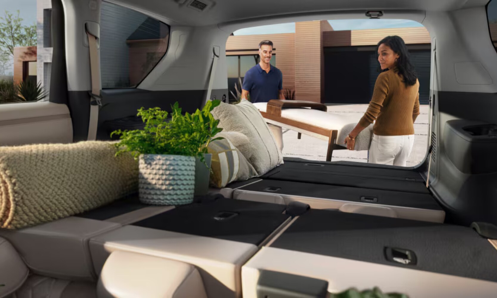 Interior image of the 2025 Nissan Armada folded rear seats with two people storing items in the open trunk