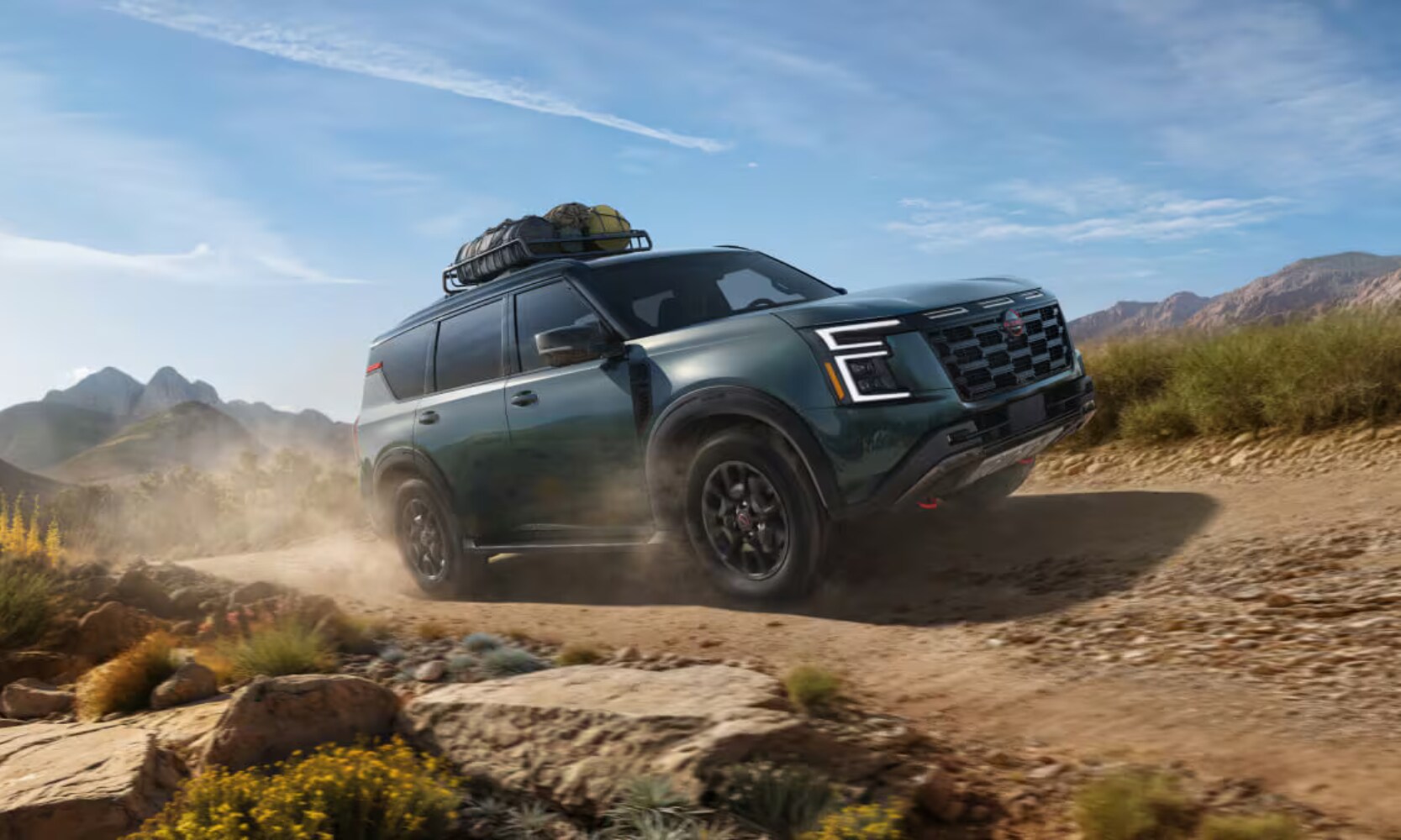 Exterior side image of a 2025 Nissan Armada towing camping gear up rocky dirt hill