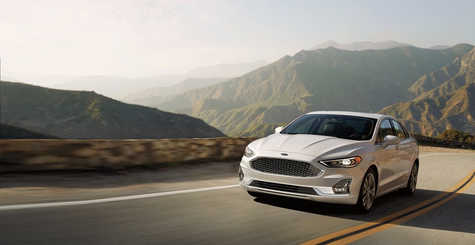 2020 Ford Fusion Titanium Sedan white on winding road with mountains in background.jpeg