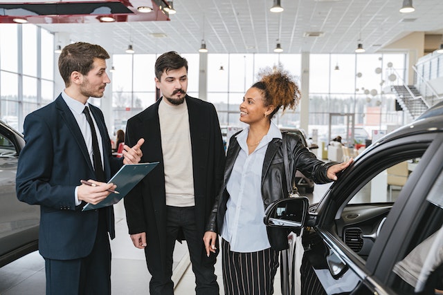 Man in Blue Business Suit Talking to Woman Touching the in Car Dealership Finance Center