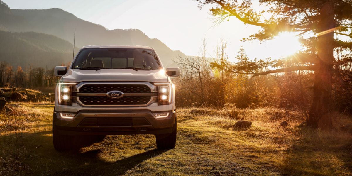2021 Ford F150 King Ranch Base CrewCab truck front view by tree mountains in back_long.jpeg