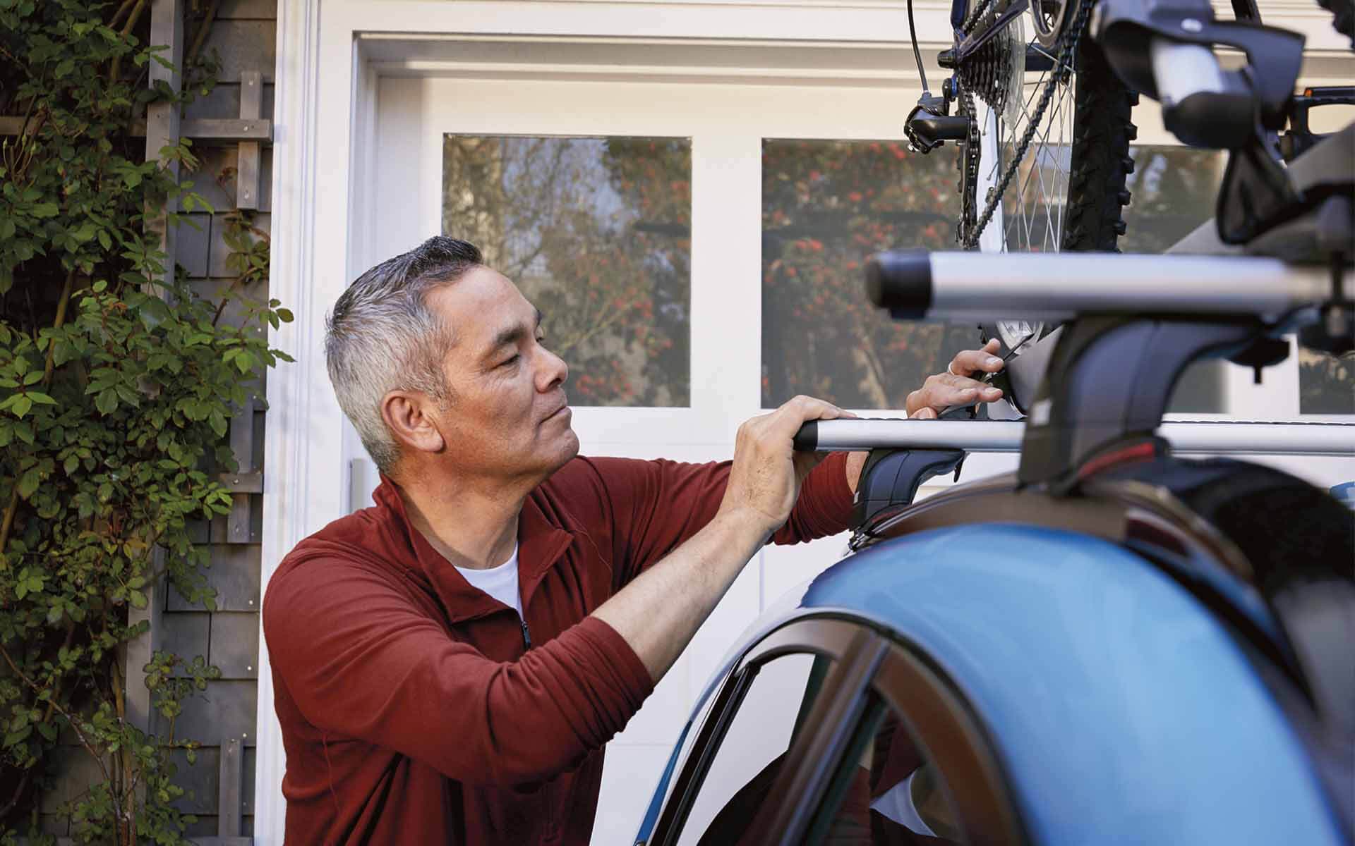 A man locking a bicycle into the Subaru Crosstrek's roof rack