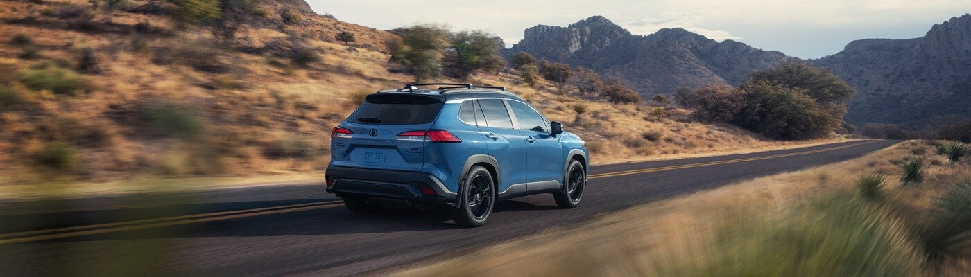 Toyota Corolla Cross Hybrid Blue Toyota Corolla Cross Hybrid XSE driving on a road in the desert