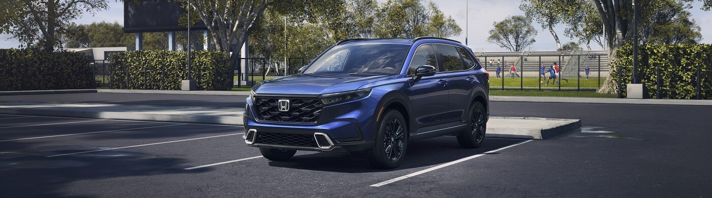 Honda CR-V Hybrid Sport Touring Blue Honda CR-V Hybrid Sport Touring parked by a rec field