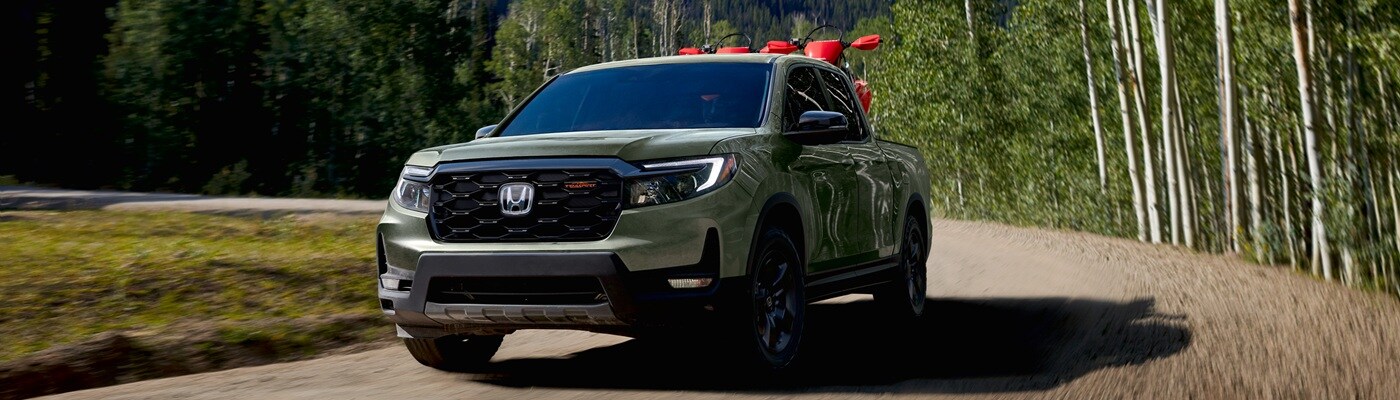New Honda Ridgeline Green Honda Ridgeline TrailSport driving away from a forest