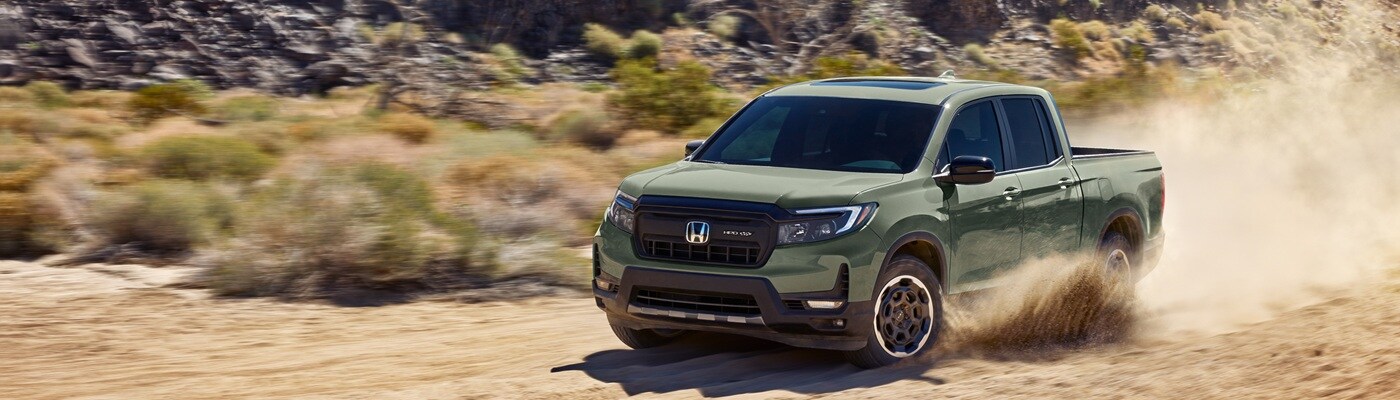 Honda Ridgeline Green Honda Ridgeline TrailSport truck driving in sand in the desert