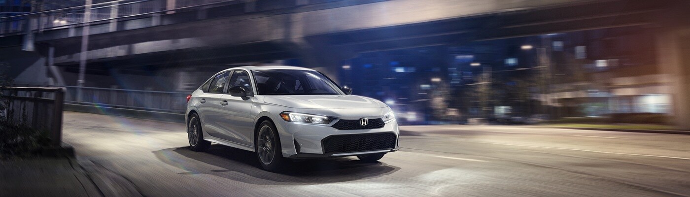 Honda Civic White Civic Sport driving on a city street at night