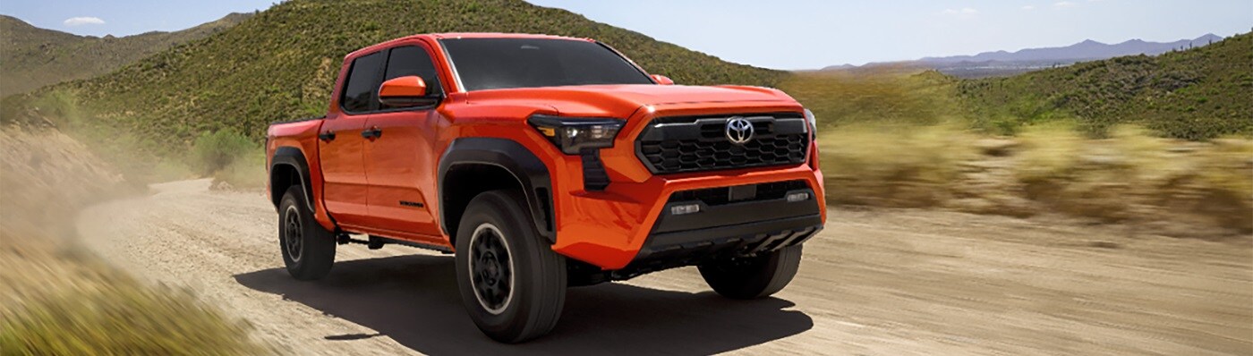 Orange Toyota Tacoma TRD Off Road driving on a
desert dirt road