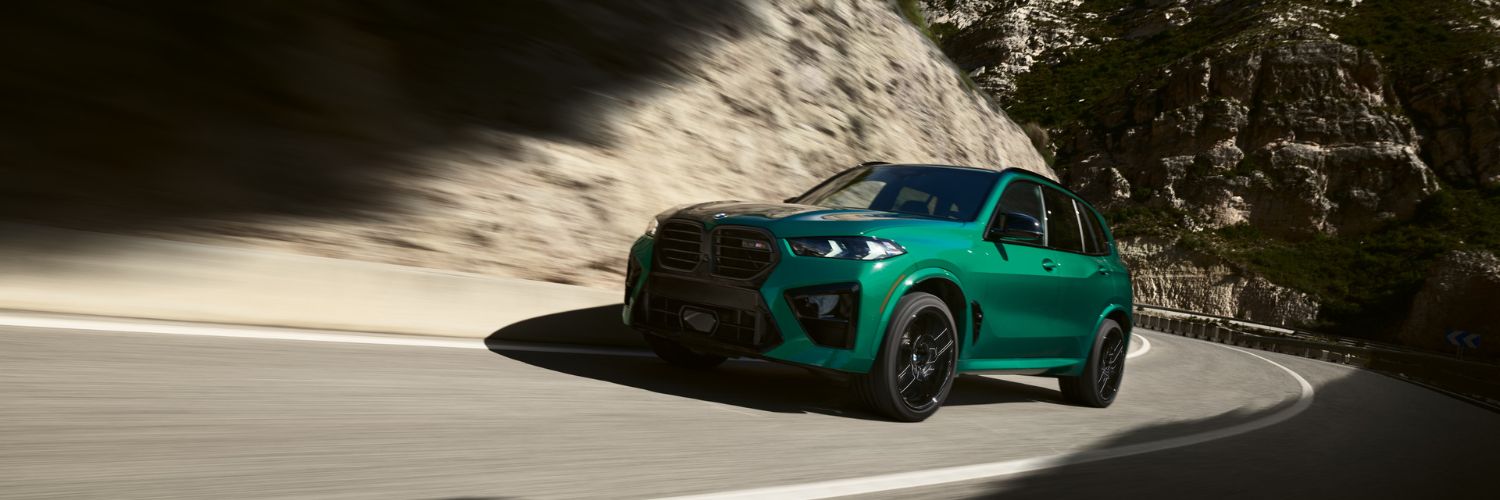 BMW X5 M performance SUV bright green BMW X5 M SUV driving up a winding mountain road