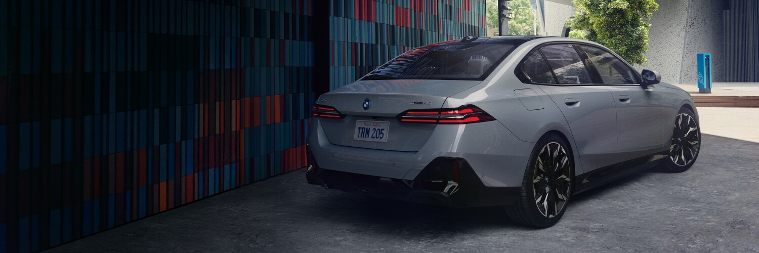 BMW i5 rear view of a silver BMW i5 sedan parked next to a colorful wall in a city