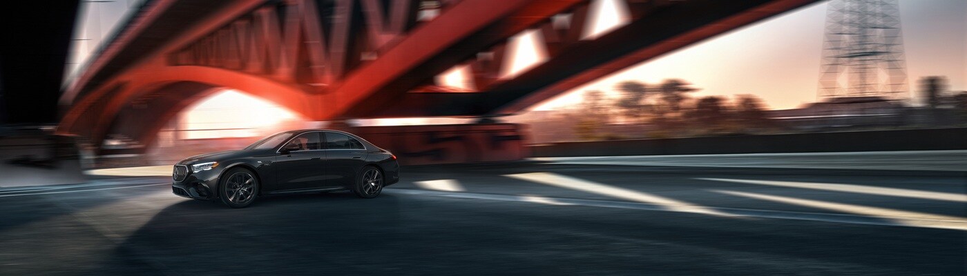 Mercedes-AMG® E-Class Black Mercedes-Benz AMG E-Class driving underneath a bridge