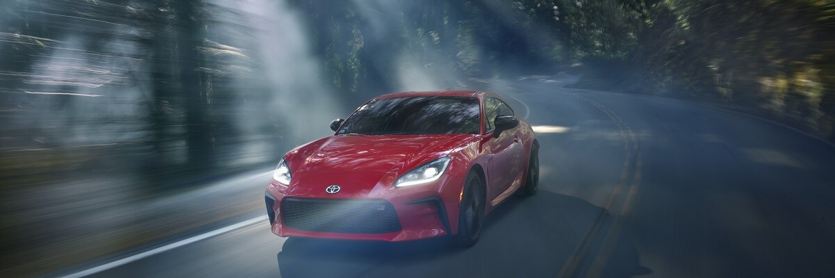 Toyota GR86 red Toyota GR86 driving on a road in the forest