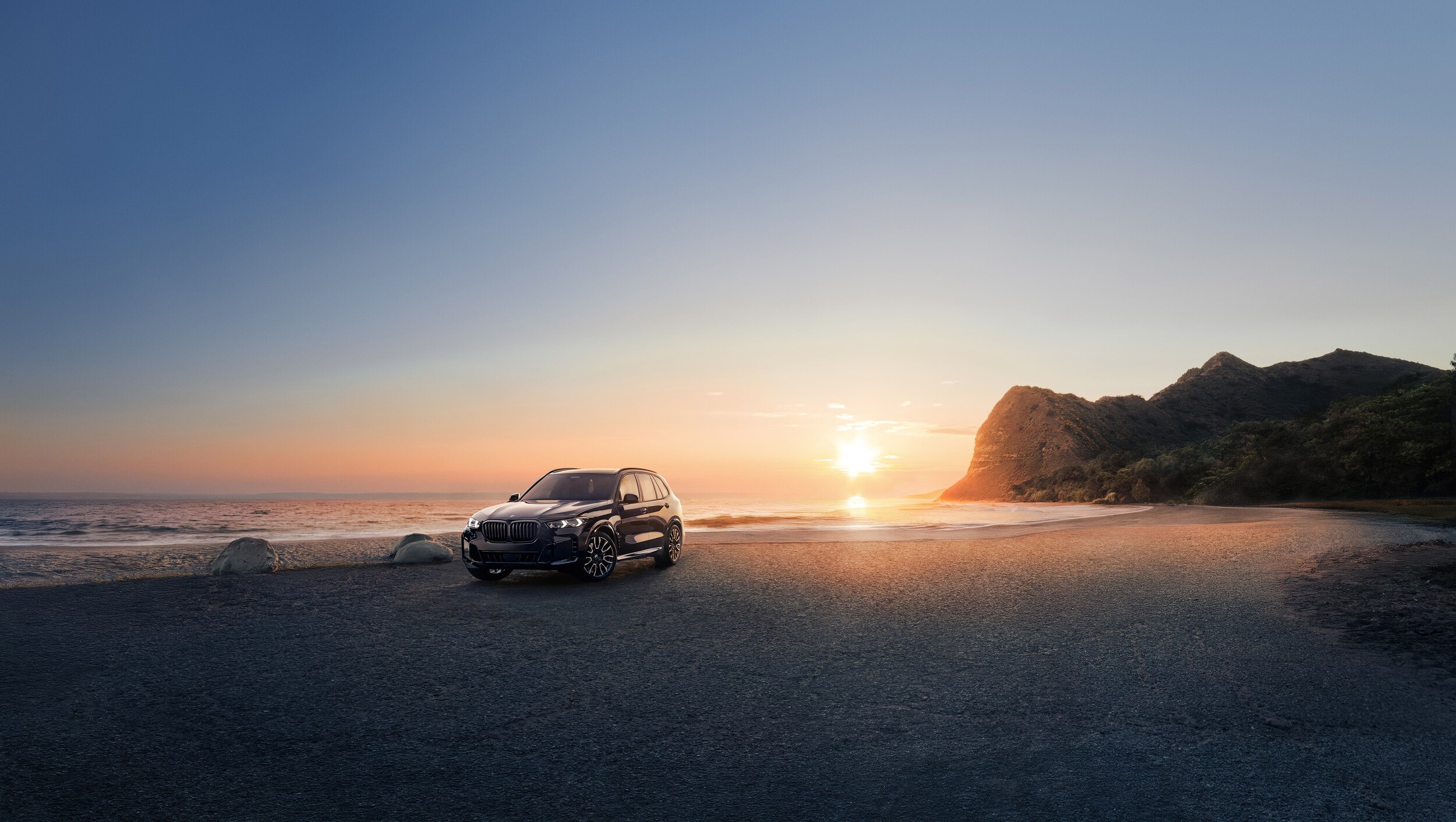 BMW X5 PHEV Black BMW X5 PHEV parked on a beach at sunset
