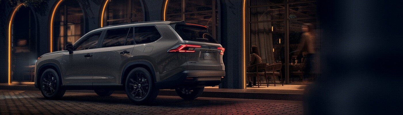 Toyota Grand Highlander Hybrid Grey Toyota Grand Highlander Hybrid Limited Nightshade parked in front of a restuarant