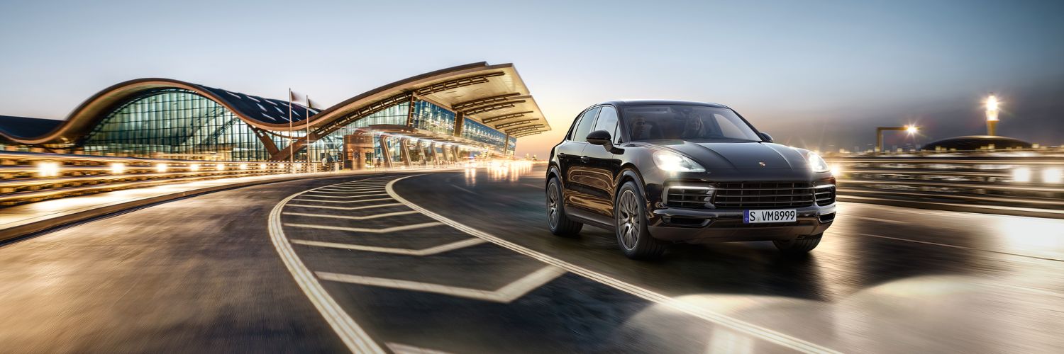 Porsche Cayenne Cayenne driving near a modern building