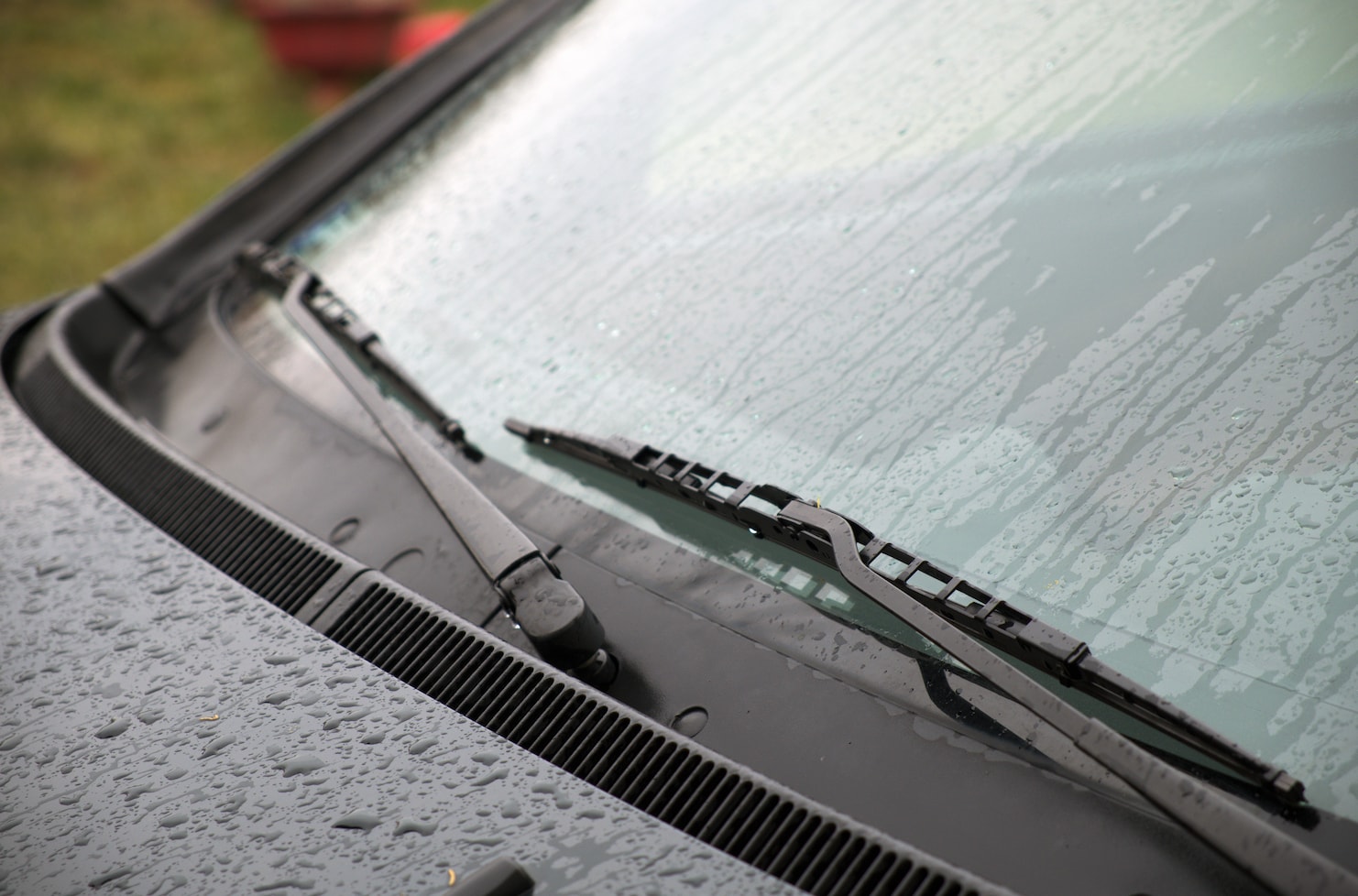 Windshield wipers wiping water off of wet wind shield.
