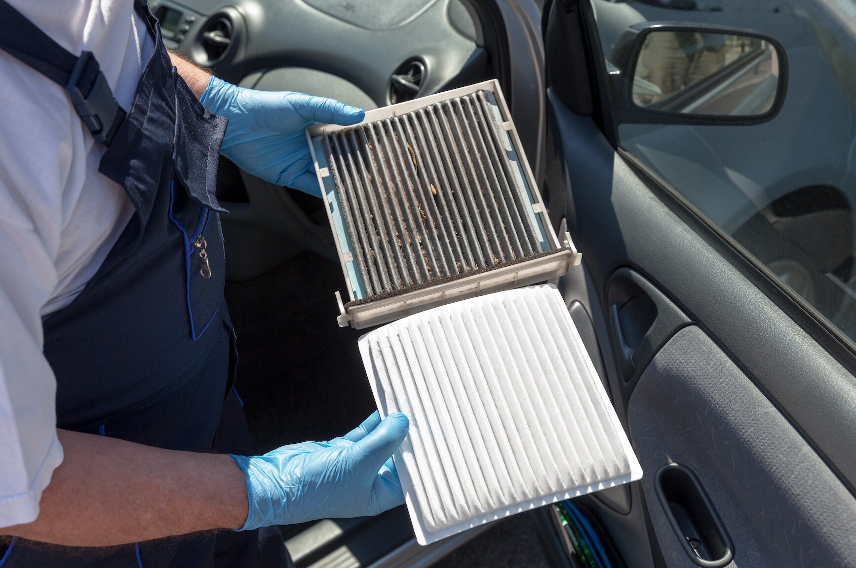 Subaru service technician holding a dirty cabin air filter in one hand and a clean one in the other.
