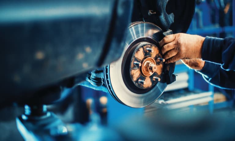man fixing car brakes