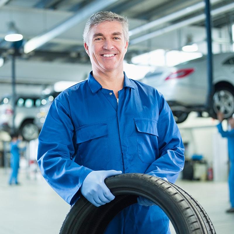 e8d8b2182423493ba6b92df4817b0f08_800x800.jpg automotive technician smiling and holding a tire