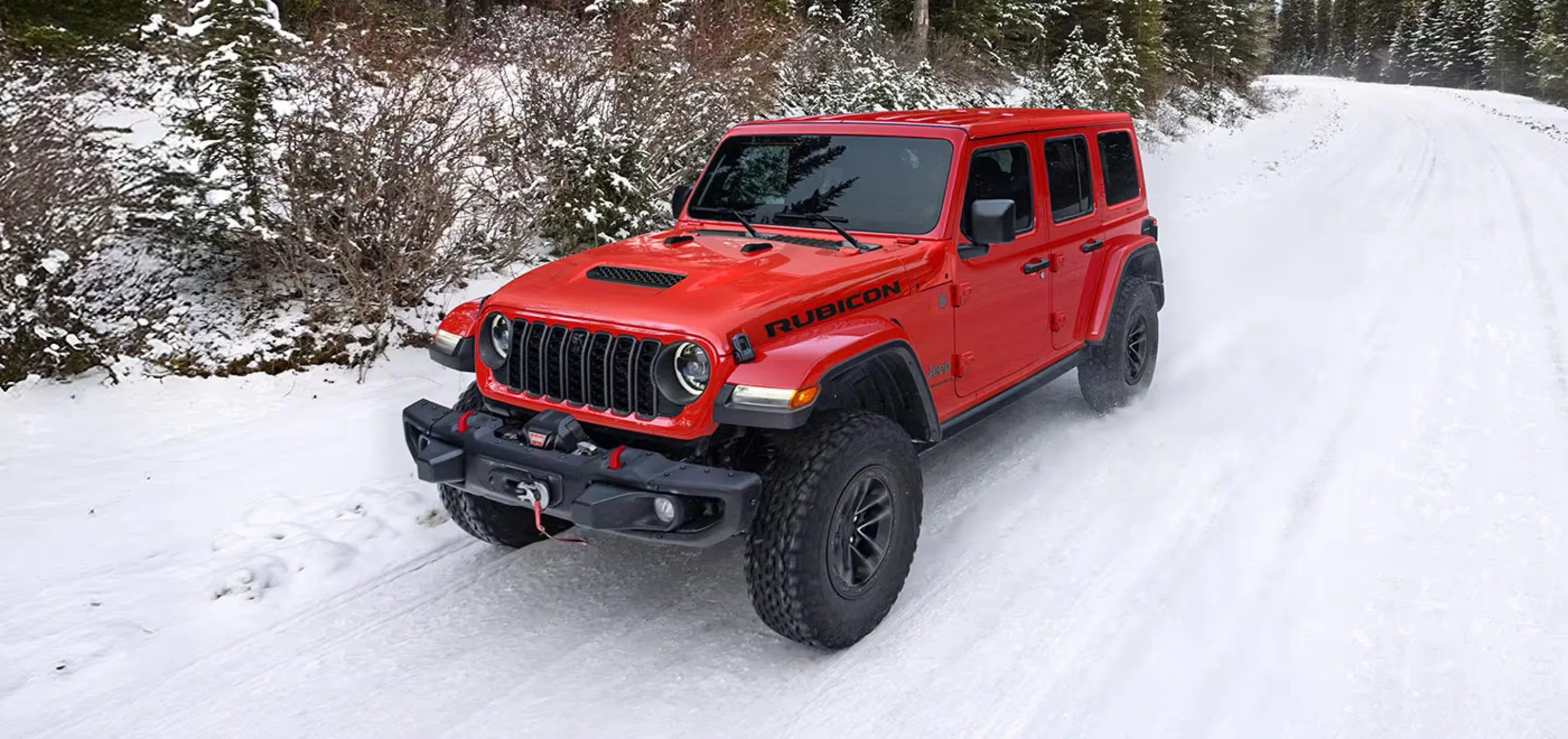 2026 Jeep Wrangler Rubicon red 4-door traveling through forest terrain