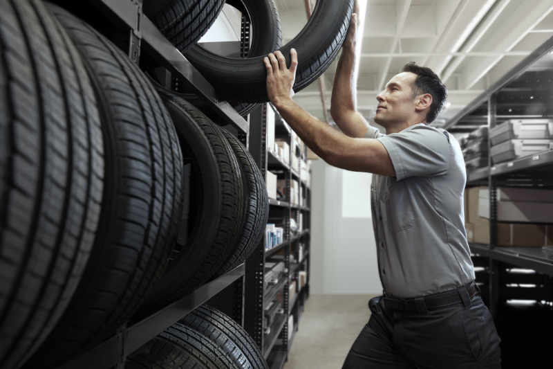 Technician Removes Lincoln Vehicle Tire from Rack