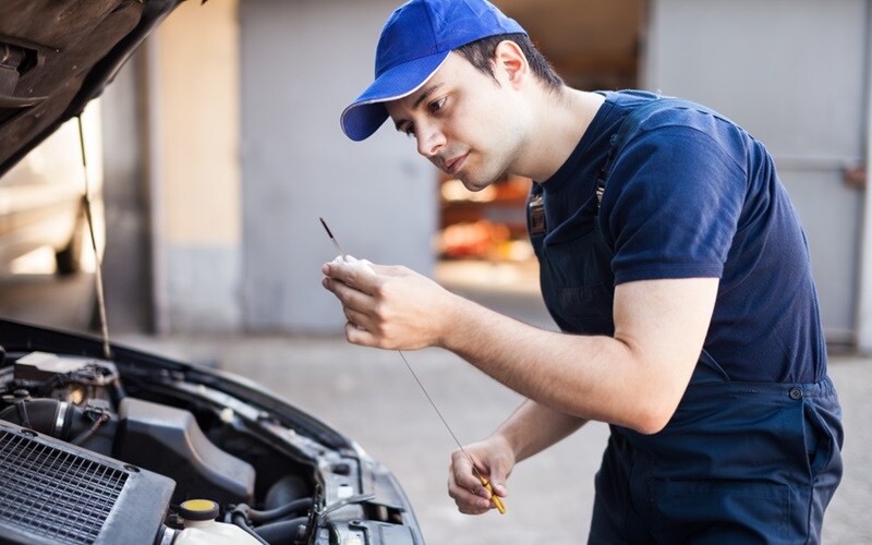 mechanic checking vehicle oil dip stick