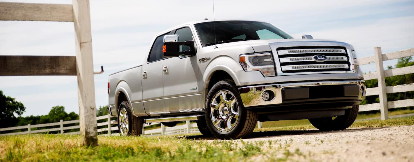 White 2014 Ford F-150 Lariat driving from a used Ford dealer near Stanton.