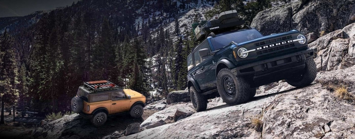 Ford%20Bronco%20for%20Sale%20-%202024%20Ford%20Bronco%20Badlands%20%26%20Outer%20Banks%20-%20Duo.jpg A blue 2024 Ford Bronco Badlands and an orange 2024 Ford Bronco Outer Banks driving up a rocky cliff.