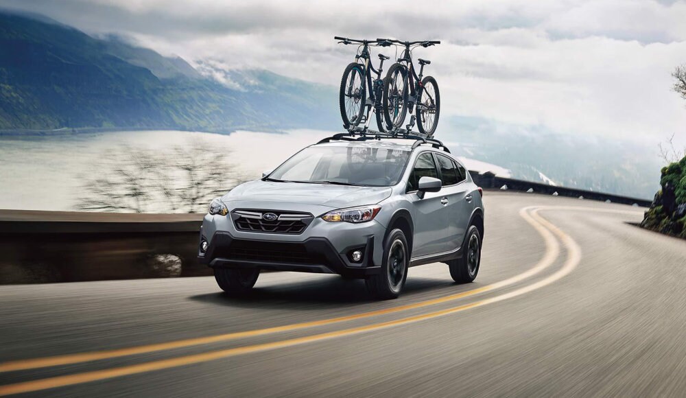 vue latérale avant d'un Subaru Crosstrek 2023 transportant des vélos sur une route en montagne