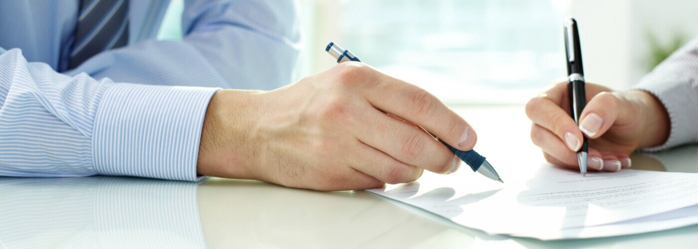 Two sets of hands signing paperwork