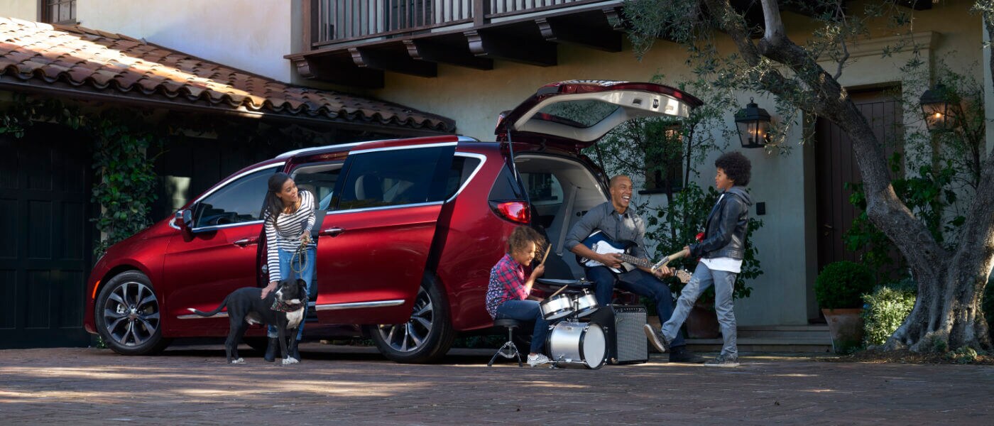 Chrysler Pacifica outside home next to a family