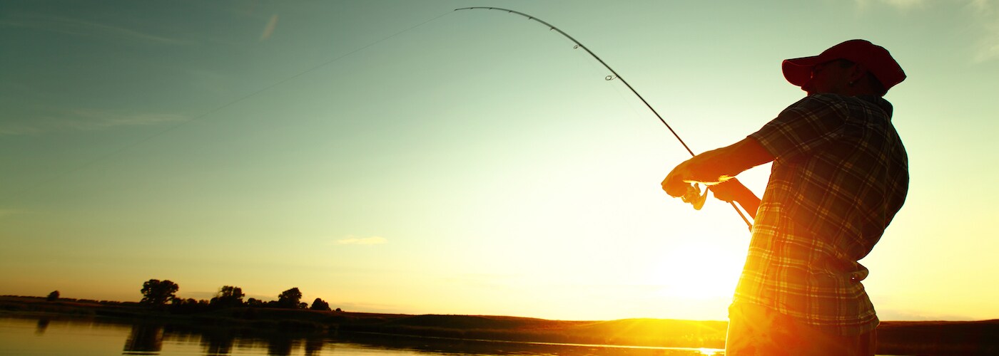 man fishing off boat at sunset
