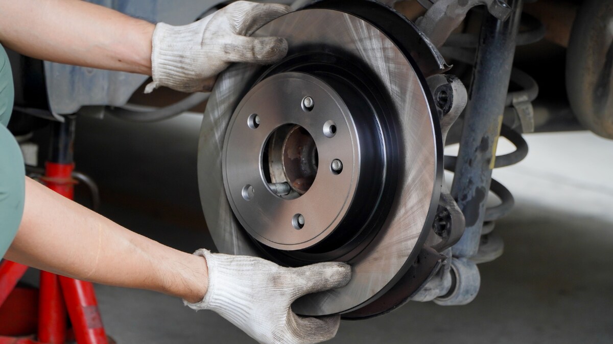 A service technician holding the brake discs of a vehicle A service technician holding the brake discs of a vehicle