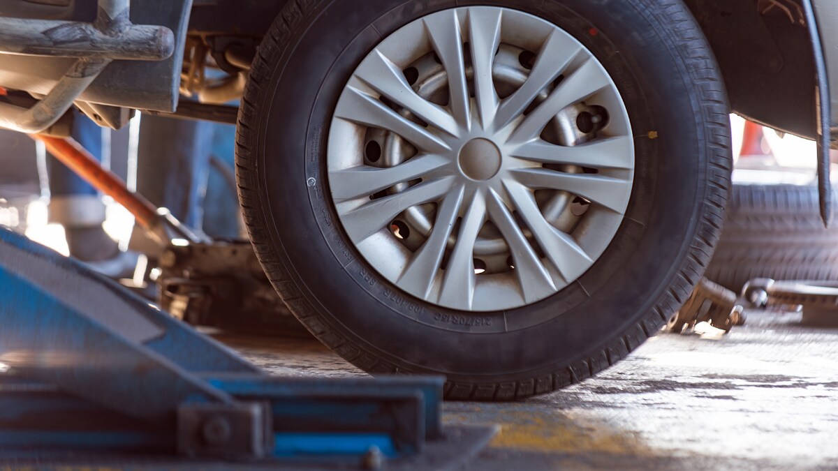 Close up of wheel of a car on a hydraulic lift before service Close up of wheel of a car on a hydraulic lift before service