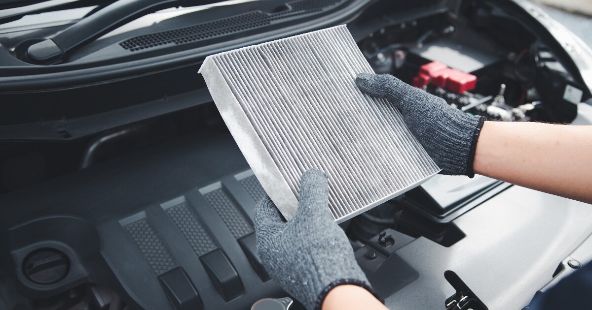 Technician performing an air filter replacement on a vehicle Technician performing an air filter replacement on a vehicle