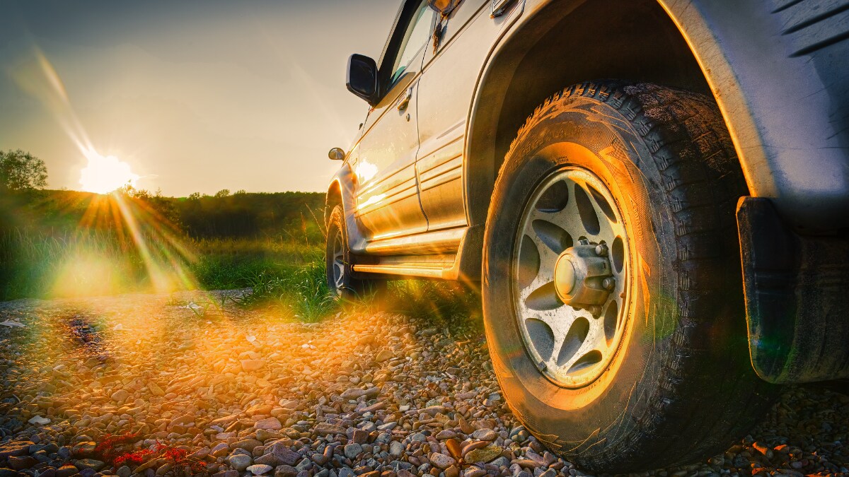 Close-up of a vehicle's rear wheel on gravel with the sun on the horizon Close-up of a vehicle's rear wheel on gravel with the sun on the horizon