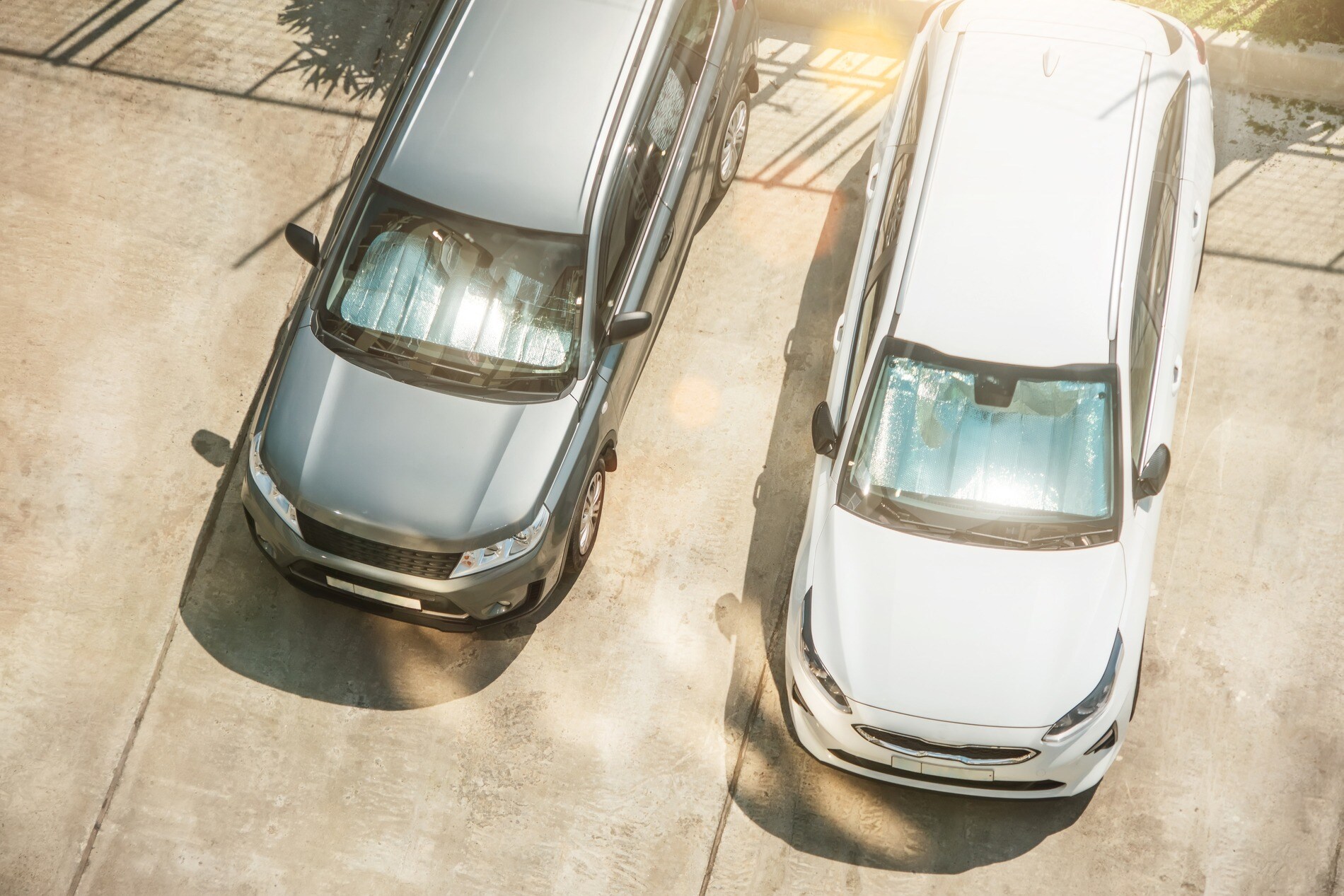 Overhead view of two cars using sunshades on their respective windshields Overhead view of two cars using sunshades on their respective windshields