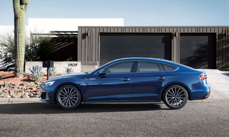 2022 Audi A5 Sportback in blue exterior parked beside modern home