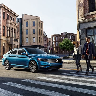 A blue Volkswagen stopped at a crosswalk