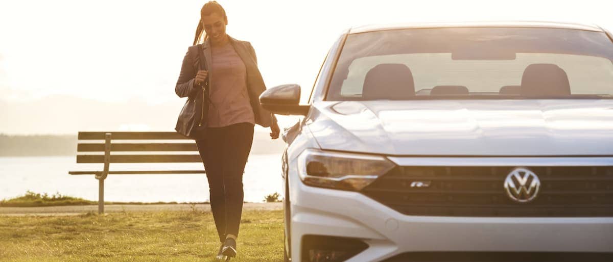 2019 VW Jetta A woman walking to her white 2019 VW Jetta