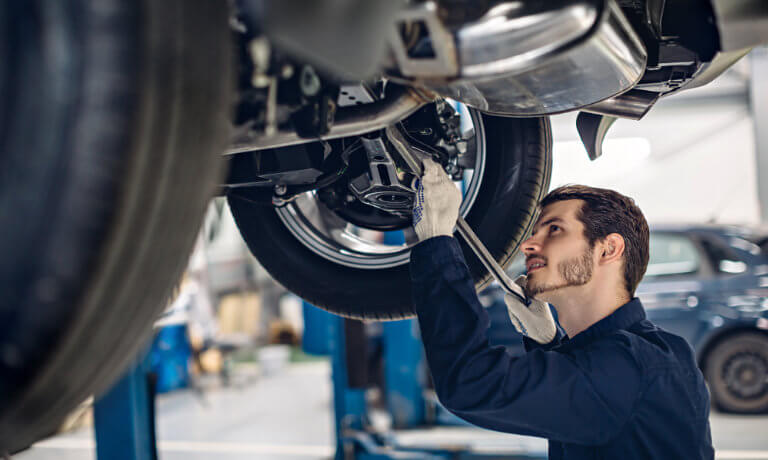 Service technician with tool under car